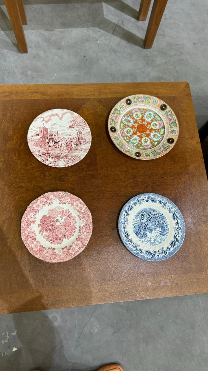 Quatro pratos decorativos sobre mesa de madeira